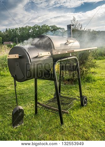 Barbeque meal being prepared using black grill with chimney in the backyard