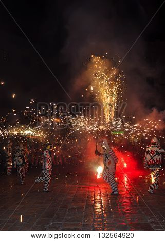 Traditional catalan spectacle called Correfocs (fire runs) or Ball de Diables (Devils' Dance). Group of individuals dressed as devils and dancing with lighting fireworks fixed on devil's pitchforks. Reus Spain. Vertical.