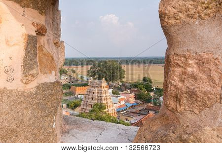 Chettinad India - October 16 2013: View out of Thirumayam Fort through one battlements opening upon village and temple gopuram.