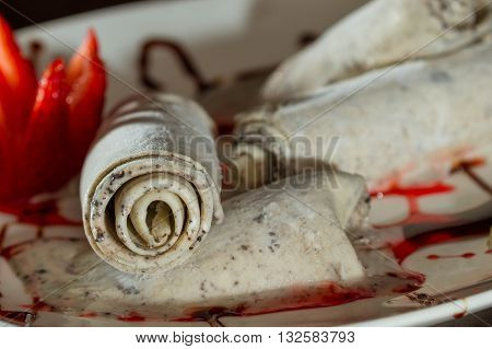 close up of an ice cream roll served at a restaurant garnished with a red strawberry
