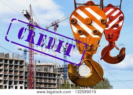 The hook of the crane and the stamp "credit " against the construction