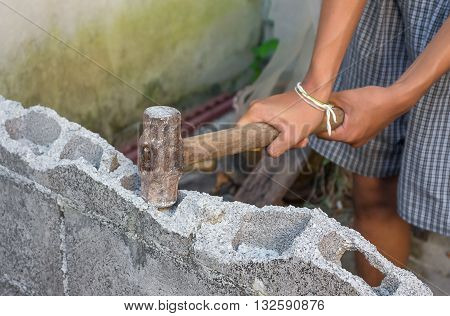 hammer in hand breaking brick wal : young power use Hammer smash a brick wall In construction : select focus Hammer Blur blurred background.