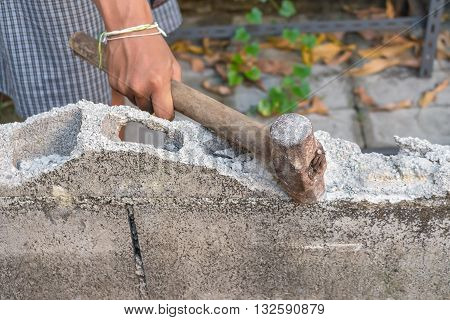 hammer in hand breaking brick wal : young power use Hammer smash a brick wall In construction : select focus Hammer Blur blurred background.