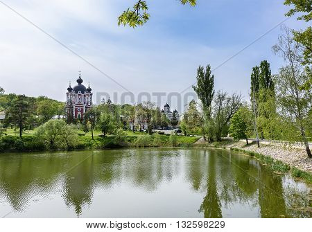 Orthodox Curchi monastery in Moldova with gren trees and blue sky with reflection on the lake