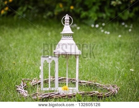 Lantern on the grass in the style of vintage mid woven wooden wreath