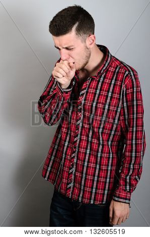 Man Coughing Into His Fist. Gray Background