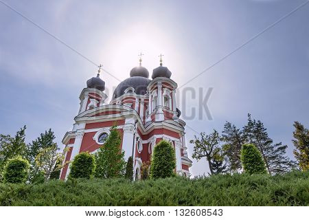 Orthodox Curchi monastery in Moldova with the sun shining at the crosses green trees and blue sky