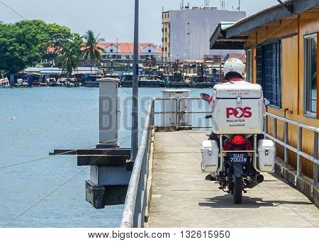 Labuan Malaysia-Apr 11,2016:A Postman Malaysia delivering post to local people on the service motorcycle April 11,2016 in water village in Kg Patau-Patau, Labuan,Malaysia.