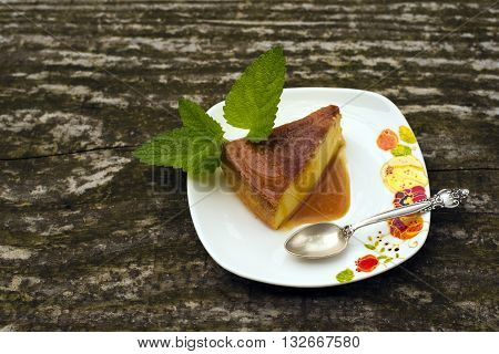 Flan - delicious creme dessert with caramel sauce.French creme caramel dessert or flan with strawberry and mint on the wooden background