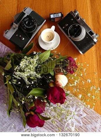 Beautiful Vintage Cameras with a colorful bouquet of flowers and decorative candles on the wooden table