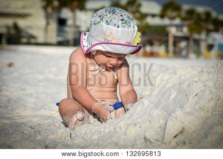 little girl sits and plays with sand on the beach