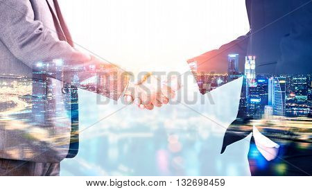 Closeup of businessmen shaking hands on illuminated night city background. Double exposure