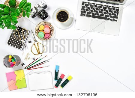 Feminine office desk workplace. Coffee cookies laptop computer and gren plant on white table background. Top view. Flat lay