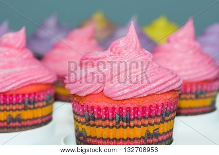 Frosted cupcakes with selective focus on front cupcake with pink frosting