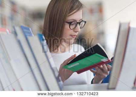 portrait of smart looking famale student girl  in collage school library,  selecting book to read from bookshelf
