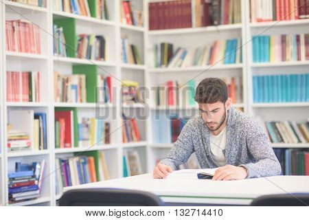 Portrait of happy student while reading book in school library. Study lessons for  exam. Hard worker and persistance concept.