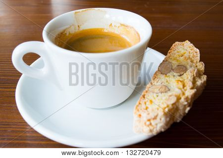 espresso in white demi-tasse with almond and lemon peel biscotti on a dark brown wooden table