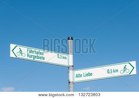 Signs that show the way for Alte Liebe and Faehrhafen and Kurgebiete in front of blue sky