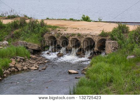 A few drainage pipes under the road. Water flowing from the pond.