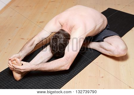 adult man is doing yoga stretching on the floor