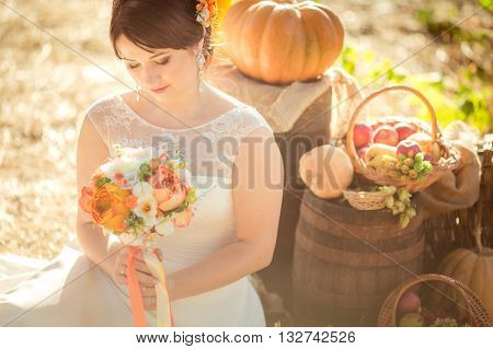 Beautiful bride in white dress in the autumn garden