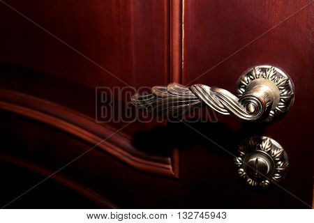 Part of brown wooden door with a metal handle and a beautiful castle