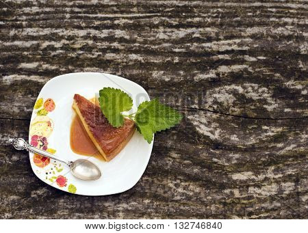Flan - delicious creme dessert with caramel sauce.French creme caramel dessert or flan with strawberry and mint on the wooden background