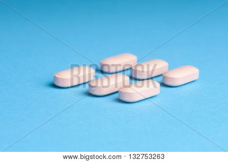 Many pills and tablets isolated on light blue background. Pharmaceutical medicament cure in container for health. Antibiotic painkiller closeup. Copy space for text.