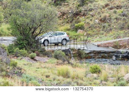 MOUNTAIN ZEBRA NATIONAL PARK SOUTH AFRICA - FEBRUARY 18 2016: A car crossing a stream on the Kranskop Loop in the Mountain Zebra National Park near Cradock