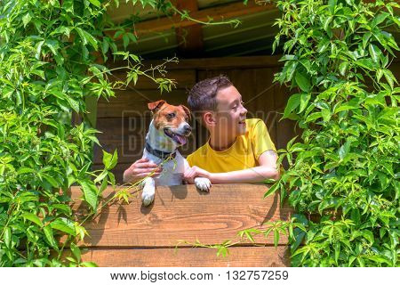 Smiling boy with dog on treehouse. Summer time!