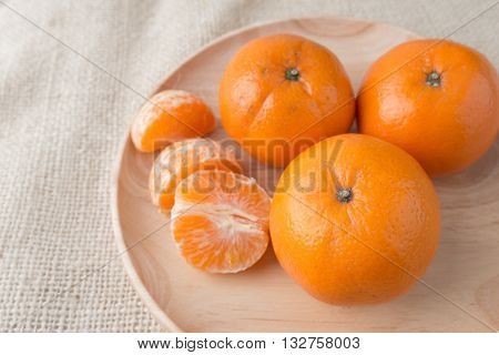 Group of mandarin oranges tangerines fruit put in wood plate on burlap sack background