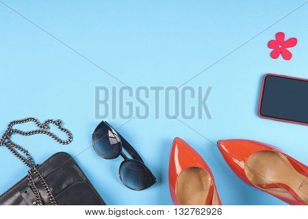 Women clothing set set of cool stuff and accessories on light blue background. Top view. Copy space for text.