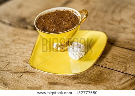 A cup of turkish coffee on the wooden table served with Turkish delight