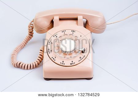 Old cream colored rotary style telephone on white