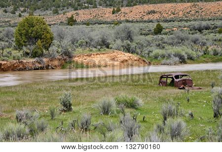 a rusty car frame sits beside the Sevier River in Utah