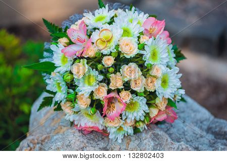 Wedding rings are on the bride's bouquet in the park