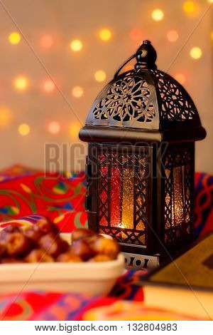 Ramadan Background - Lantern dish of dates and Quraan on Ramadan colorful fabrics