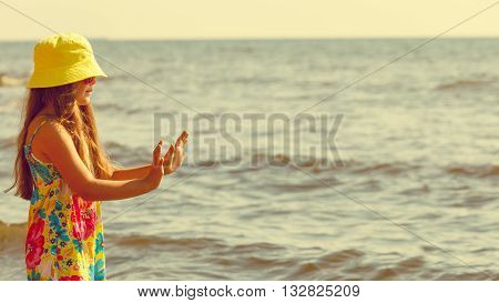 Joy and fun. Lovely little girl wearing summer clothes having fun outside on beach seaside. Child spending time playing near to sea ocean.