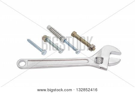 Adjustable wrench next to the bolts with with a hex nut lag screws and plastic wall plug on a light background