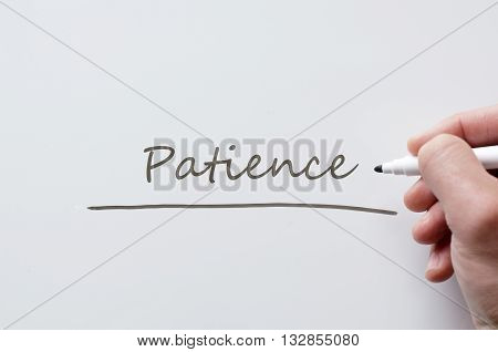 Human hand writing patience on whiteboard .