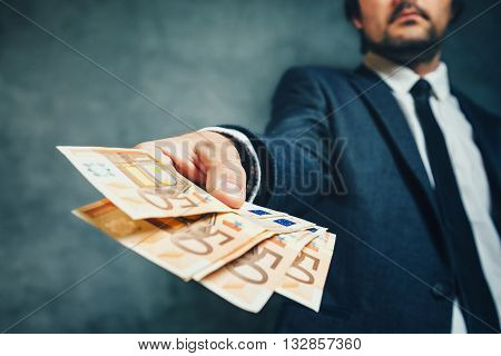 Businessman from bank offering money loan in euro banknotes selective focus.