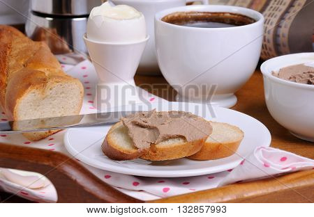 A slice of toast spread with liver pate for breakfast and a cup of coffee on a tray