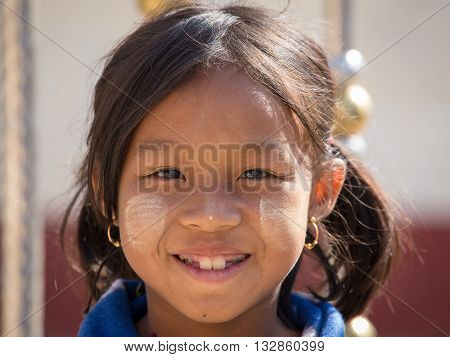 INLE LAKE MYANMAR - JANUARY 12 2016: Unidentified young Myanmar girl with thanaka on her smile face is happiness. Thanaka is a yellowish-white cosmetic paste made from ground bark.
