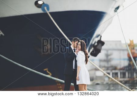 Happy bride and groom hugging near ship.