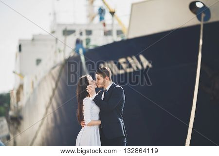 Happy bride and groom hugging near ship.