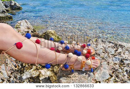 woman advertises traditional greek sandals gladiator on beach