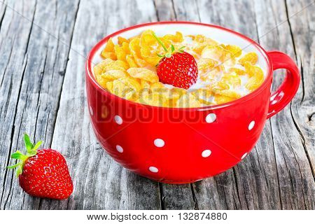 corn flakes with milk and strawberry in a red cup on an old rustic table studio lightrs close-up top view
