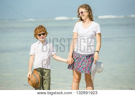 Yound caucasian mother and son having great family time on tropical beach on vacation