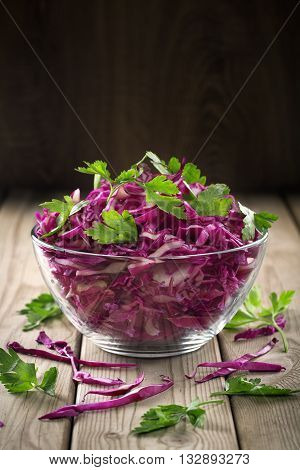 Natural product lies in a transparent salad bowl. Dark background.
