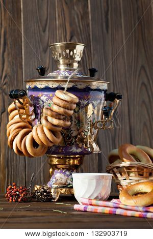 Russian traditional samovar with colorful donut and a cup of tea with bagels on a wooden background